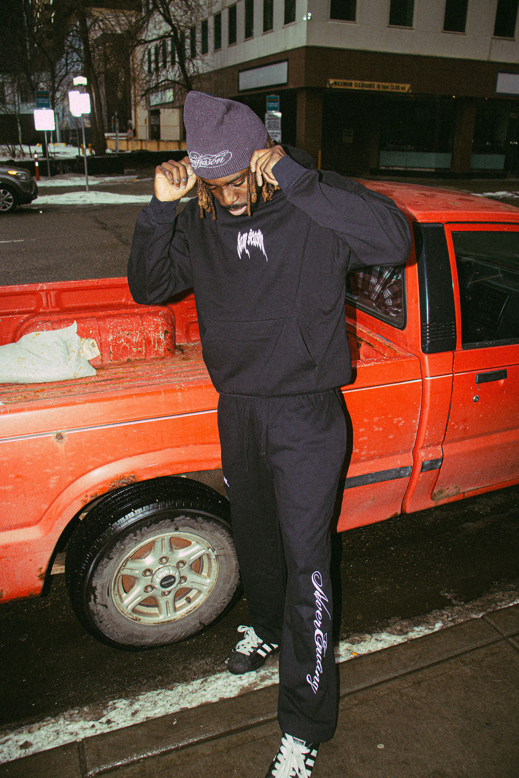 Model wearing black streetwear hoodie and sweatpants styled as a matching set, modern urban look