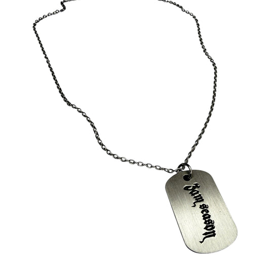 Silver dog tag necklace with engraved text on a white background